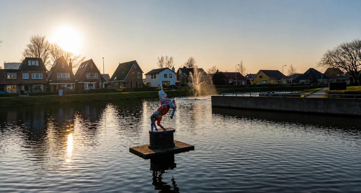 Water met een fontein en woningen vlak bij de boerderij